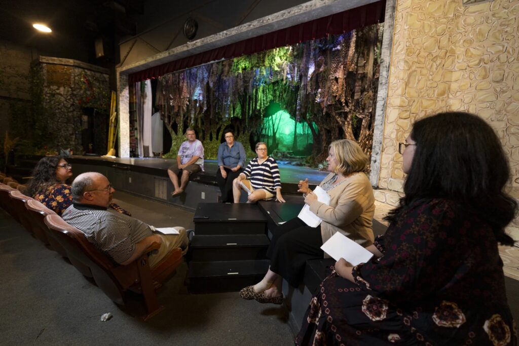 A photo of people sitting around a stage in a theater