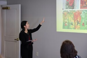 A student stands before community members giving a presentations